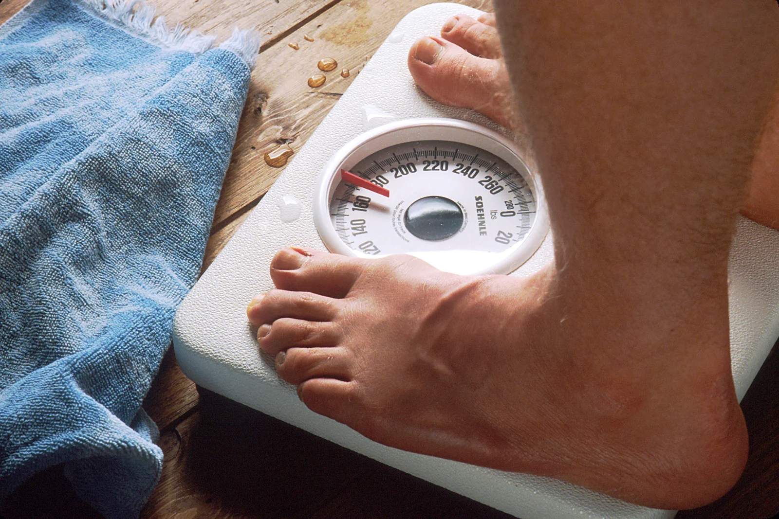 Pieds nus posés sur une balance connectée blanche au sol d'une salle de bain