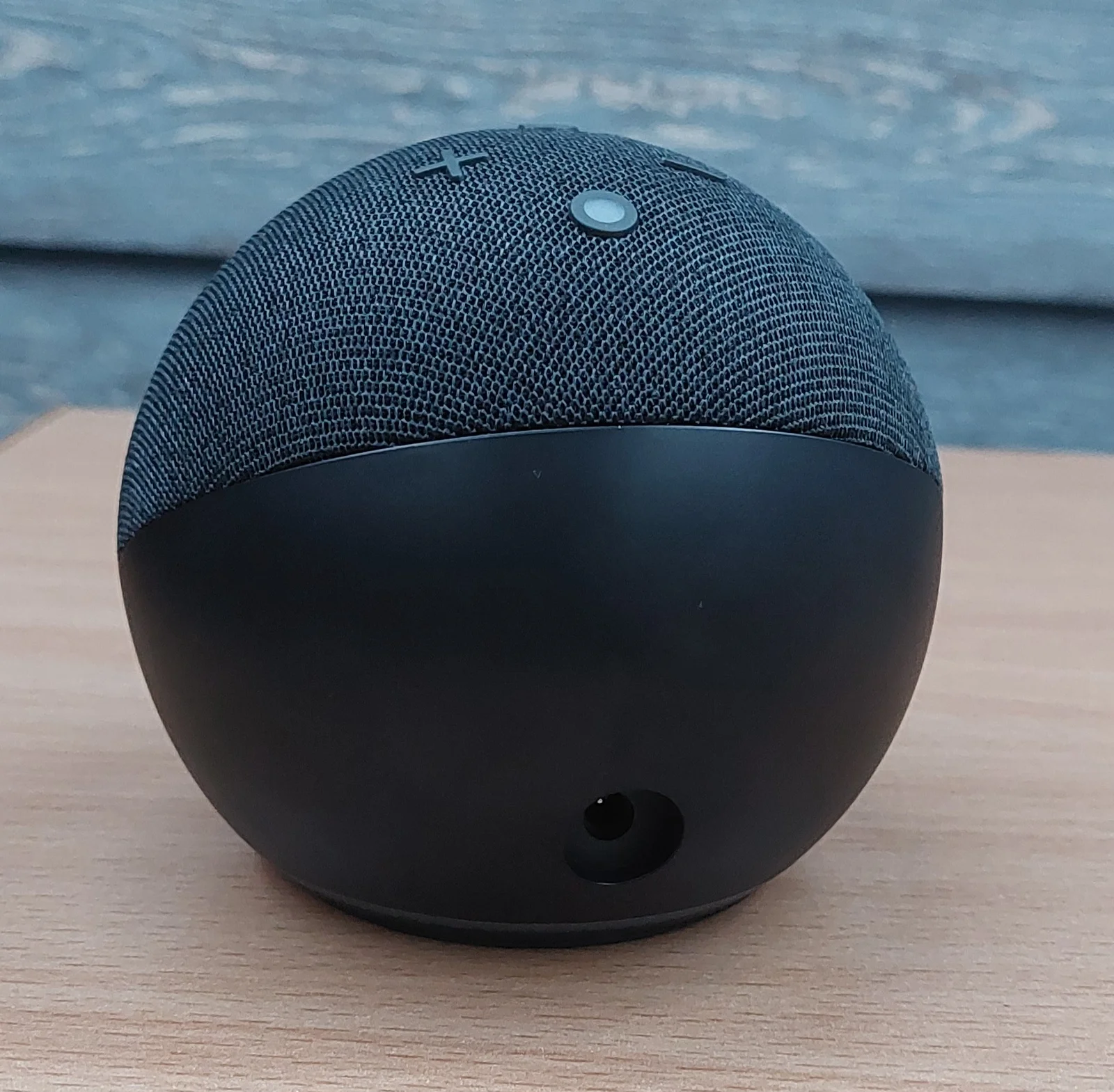 Enceinte connectée noire posée sur une table en bois dans un intérieur chaleureux