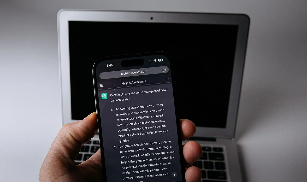 Smartphone affichant ChatGPT posé à côté d'un ordinateur portable, illustrant la préparation d'une automatisation domotique