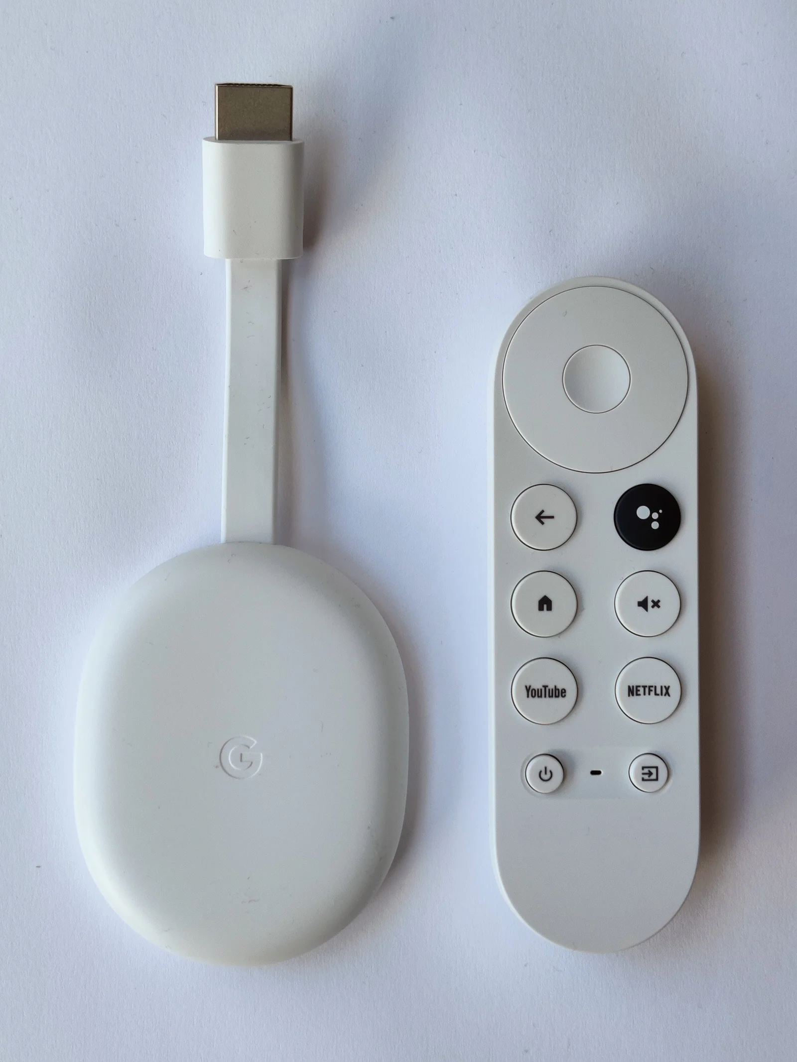 Chromecast avec Google TV et sa télécommande posés sur une surface blanche