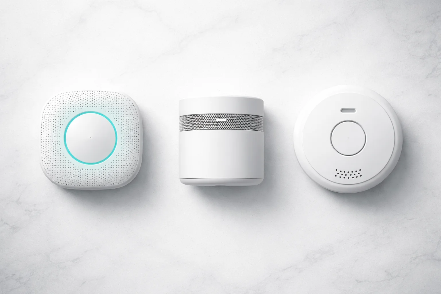 Comparatif de trois modèles de détecteurs de fumée connectés sur fond blanc