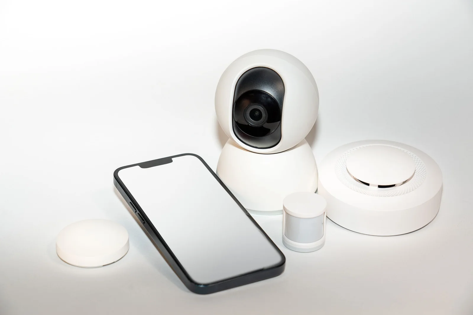 Collection de gadgets de sécurité connectée avec un smartphone affichant leur application