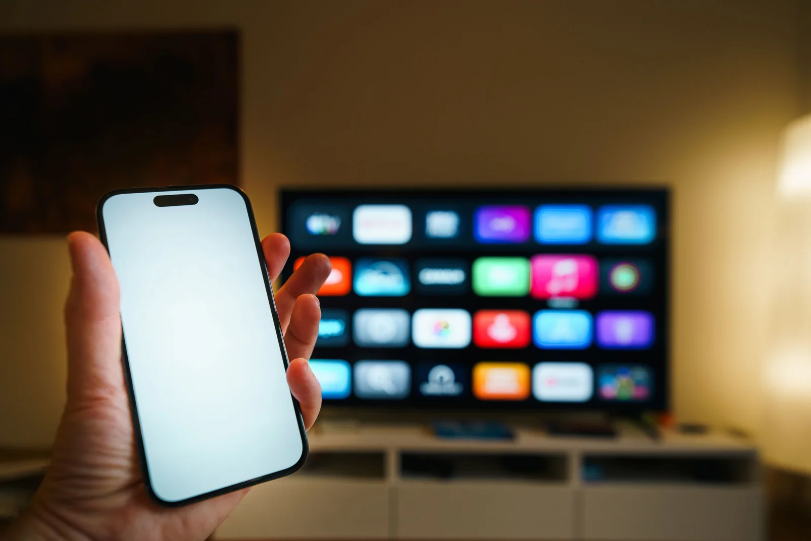 Smartphone au premier plan avec une smart TV affichant des applications dans un salon cosy