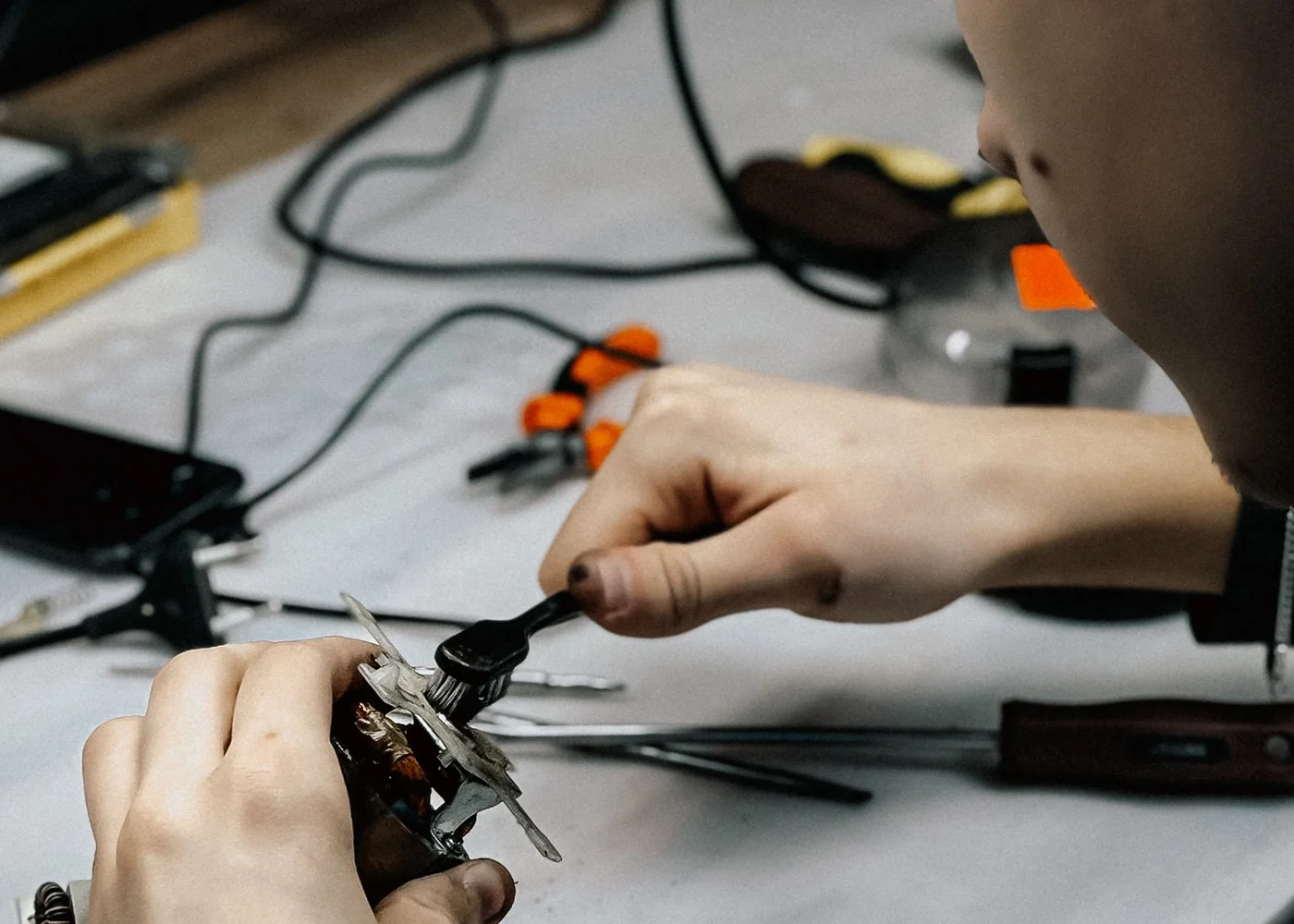 Technicien réparant un appareil électronique connecté avec des outils de précision