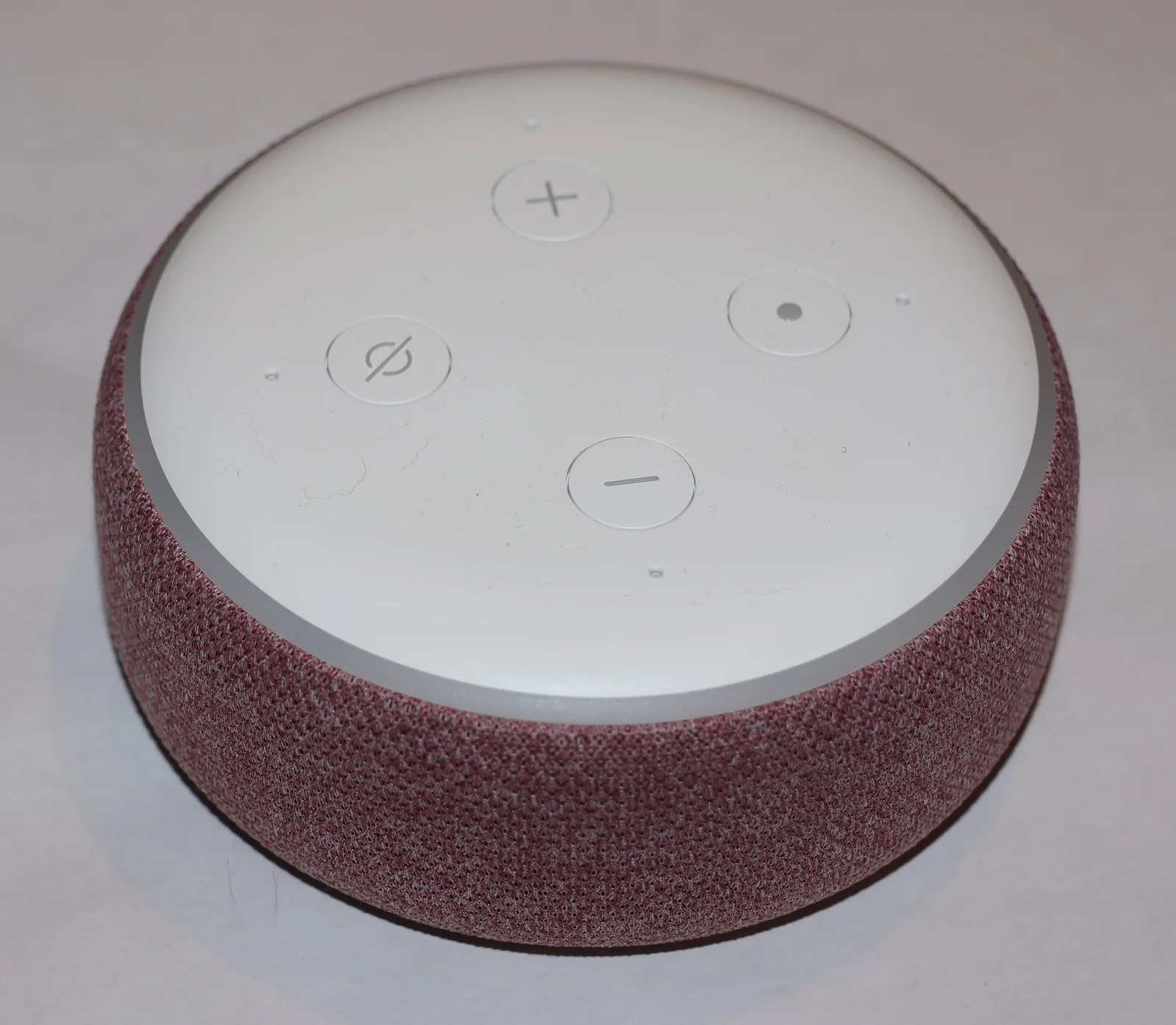 Enceinte connectée rouge posée sur une surface claire, illustrant un boîtier vocal domestique compact