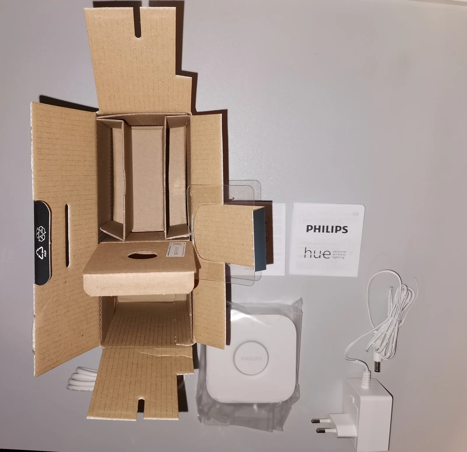 Boîtes d'emballage de passerelle domotique posées sur une table en bois clair, illustrant le déballage d'un hub connecté