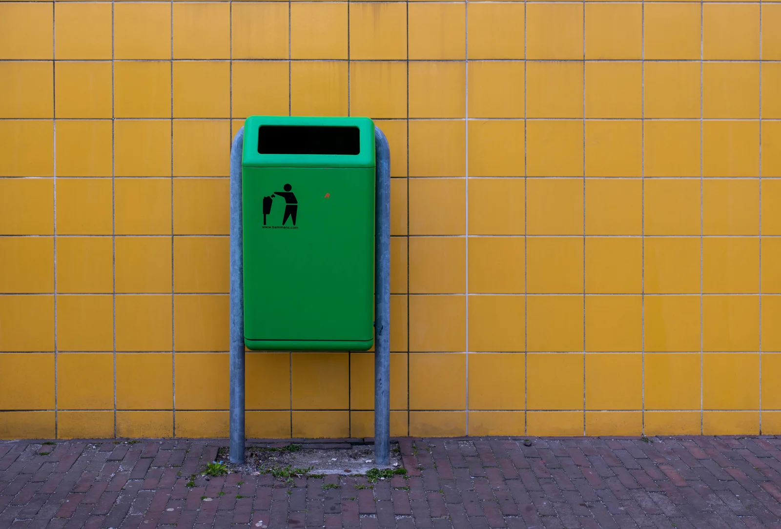Poubelle de tri vert vif contre un mur jaune — bac de recyclage connecté cuisine