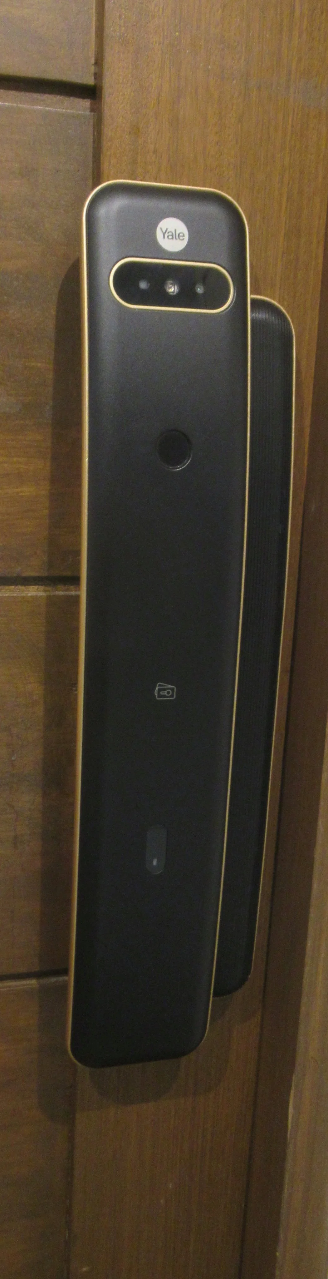 Serrure connectée à reconnaissance faciale installée sur une porte d'entrée en bois clair