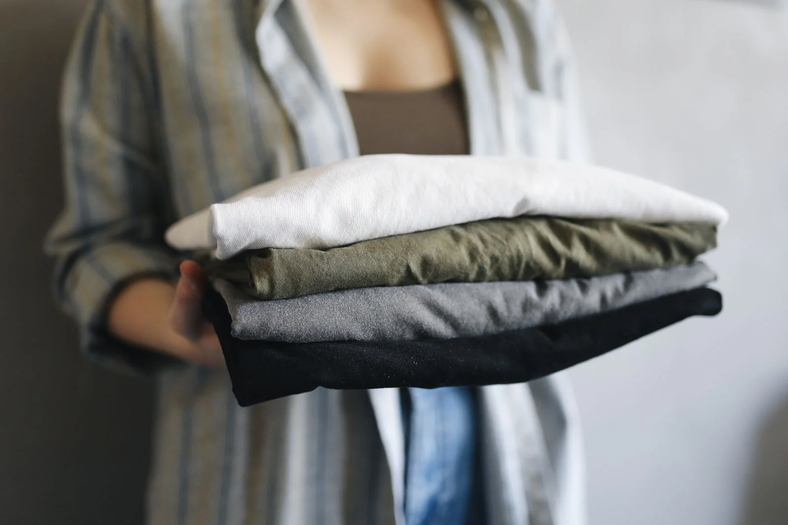 Personne tenant une pile de vêtements pliés dans les bras