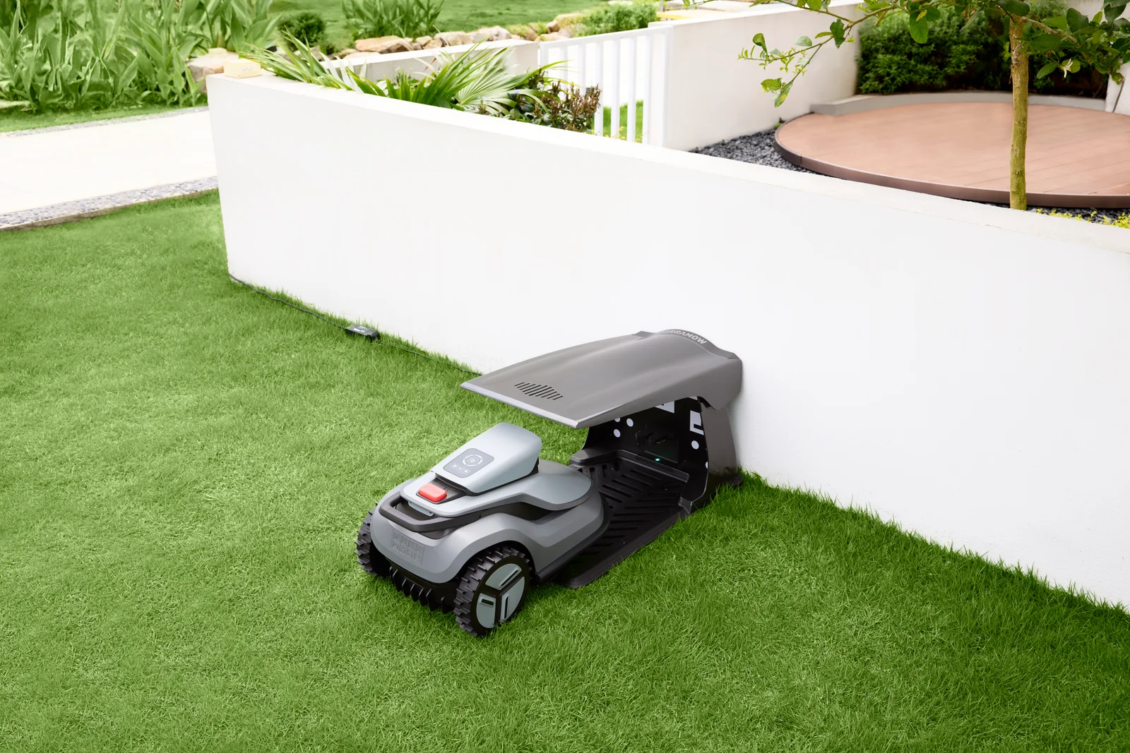 Station de charge TerraMow discrètement intégrée dans un muret de jardin, sans câble apparent