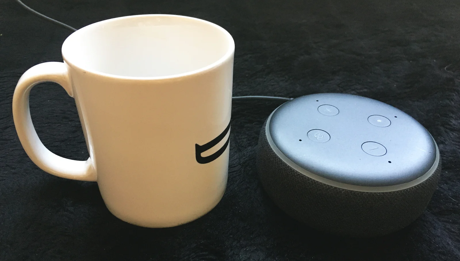 Enceinte connectée Amazon Echo Dot posée à côté d'une tasse de café sur un plan de travail