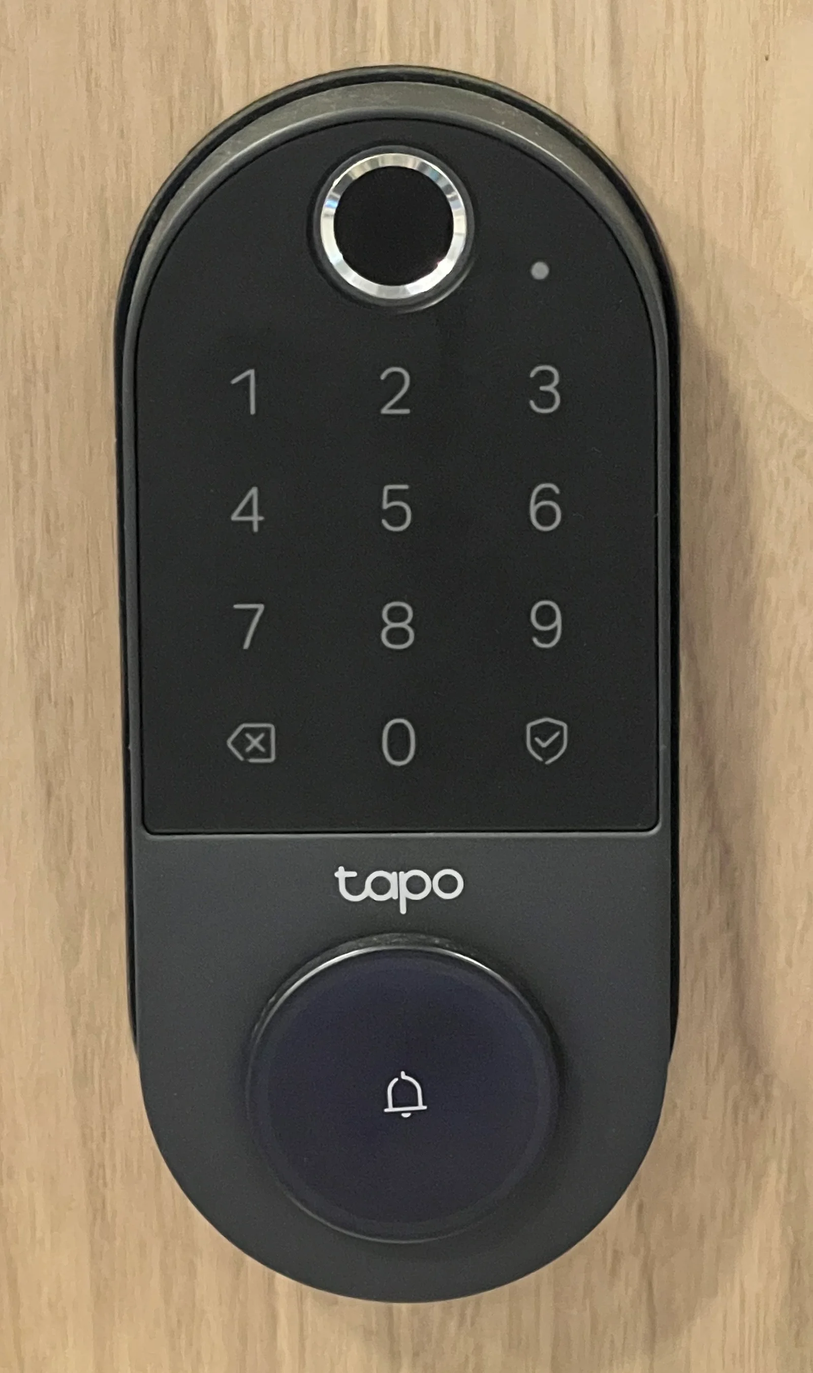 Serrure connectée TP-Link Tapo installée sur une porte d'entrée moderne