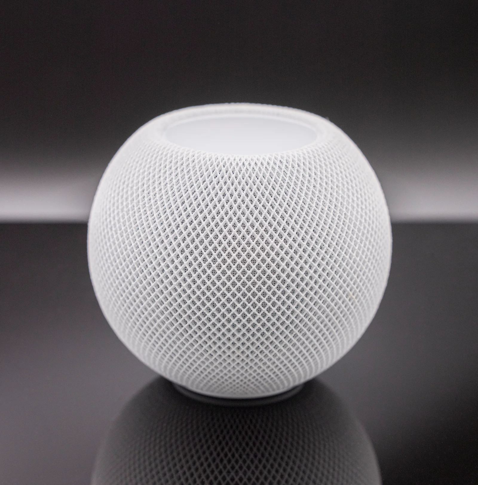 HomePod mini blanc posé sur une étagère, faisant office de bordure Thread pour l'écosystème Apple Home