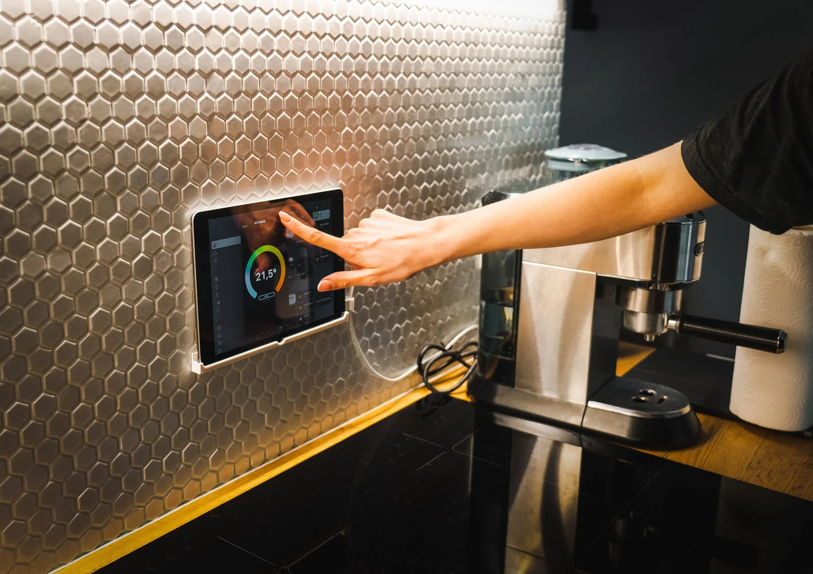 Main utilisant une tablette pour piloter les équipements connectés d'une cuisine moderne
