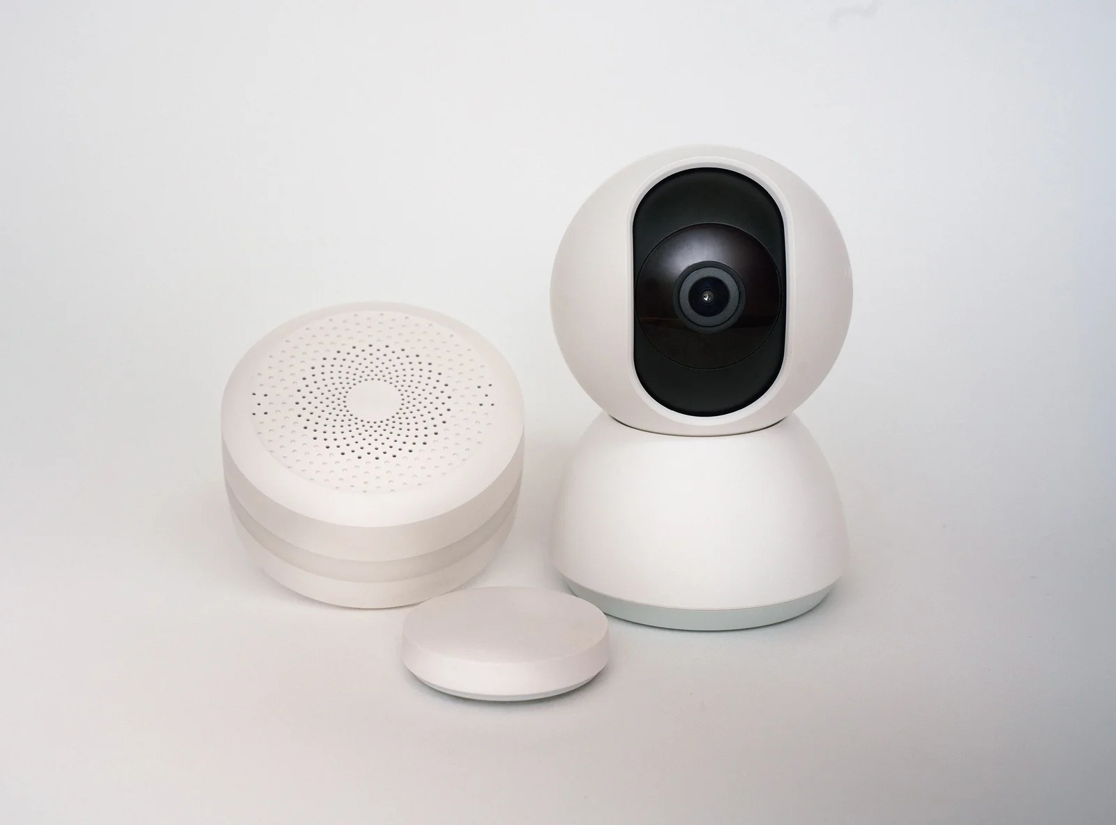 Ensemble d'objets connectés blancs, dont une caméra et des capteurs, disposés sur un meuble minimaliste